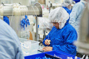 worker in sterile garb assembling IV lines