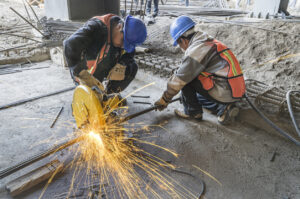 Man grinding metal tubes with protective equipment
