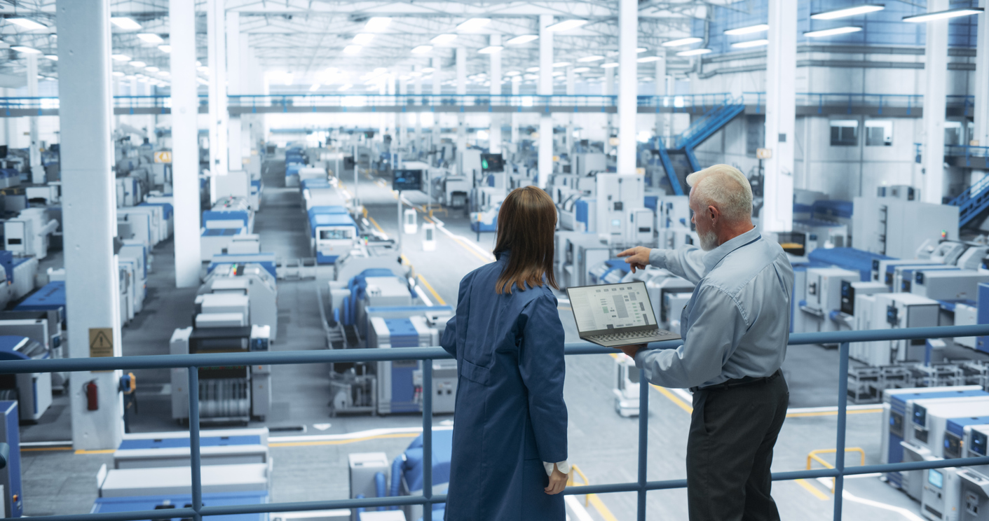 Managers standing on a platform overlooking a manufacturing facility